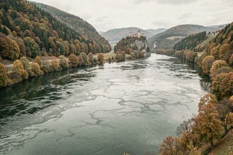 Vue panoramique du Danube traversant une vallée d'Europe centrale avec des collines boisées et des reflets sur l'eau