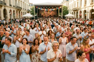 Foule enthousiaste lors d'un festival de musique gratuit en plein air à Lyon, avec scène ouverte et architecture lyonnaise en arrière-plan